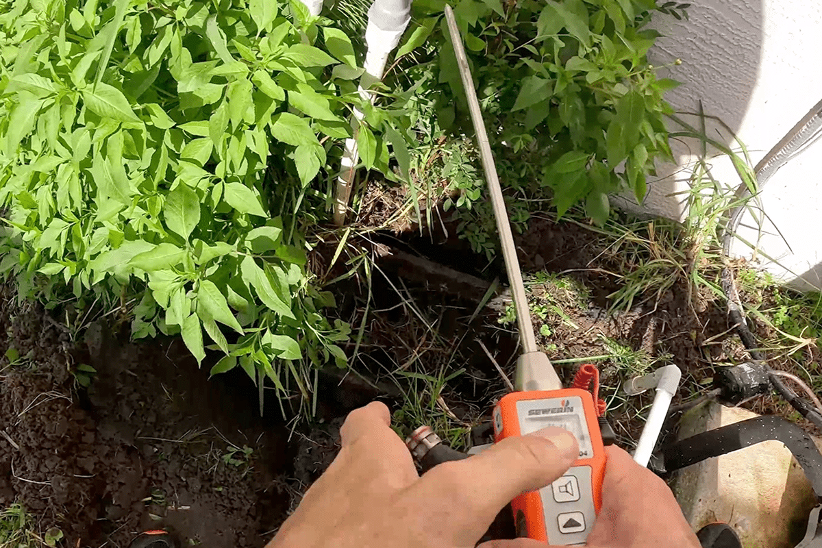 Leak detector checking outside pipes during a field service call